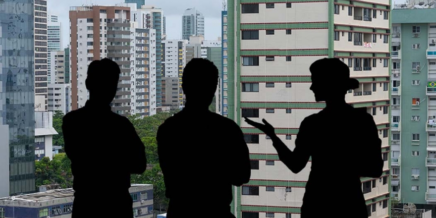 Homem de meia idade, com cabelos pretos e barba aparada, terno, gravata e óculos, à frente de um computador. Em primeiro plano uma imagem da deusa da justiça, de costas.